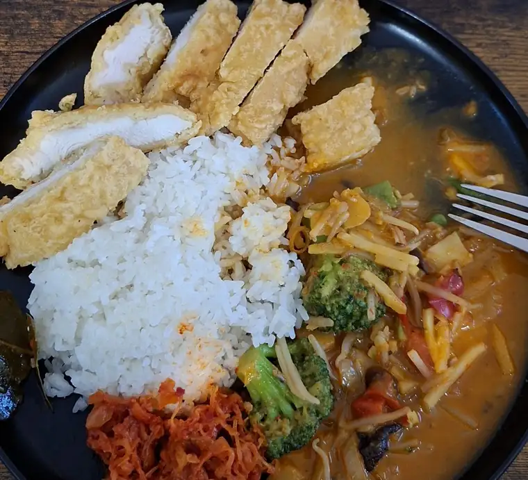 Kurczak katsu z ryżem i sosem curry na czarnym talerzu