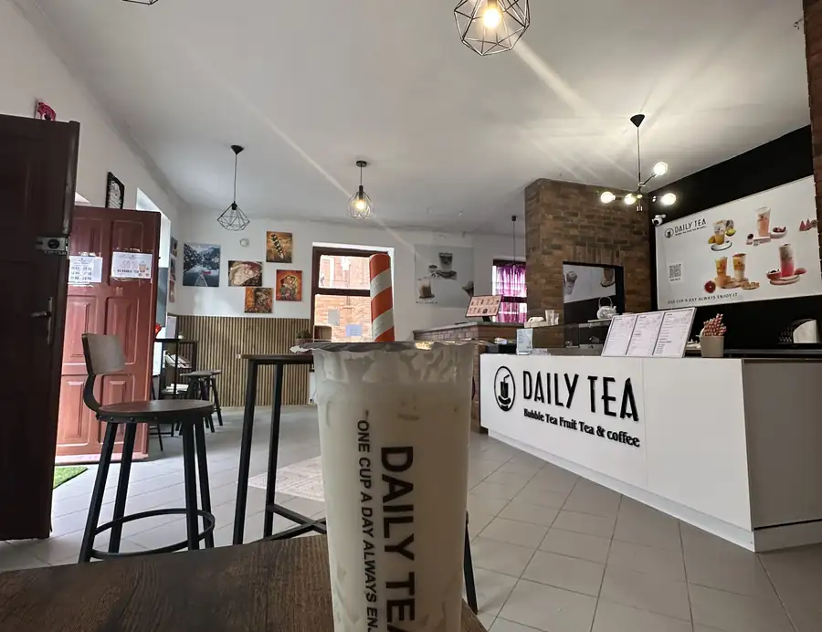 Jasna sala z ladą Daily Tea i kubkiem bubble tea na pierwszym planie